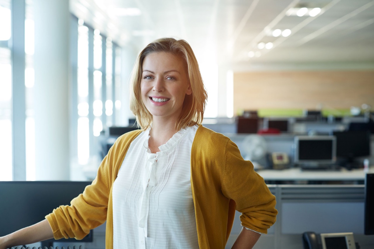 Une femme debout dans un bureau et souriant - Couverture de la brochure sur la flexibilité