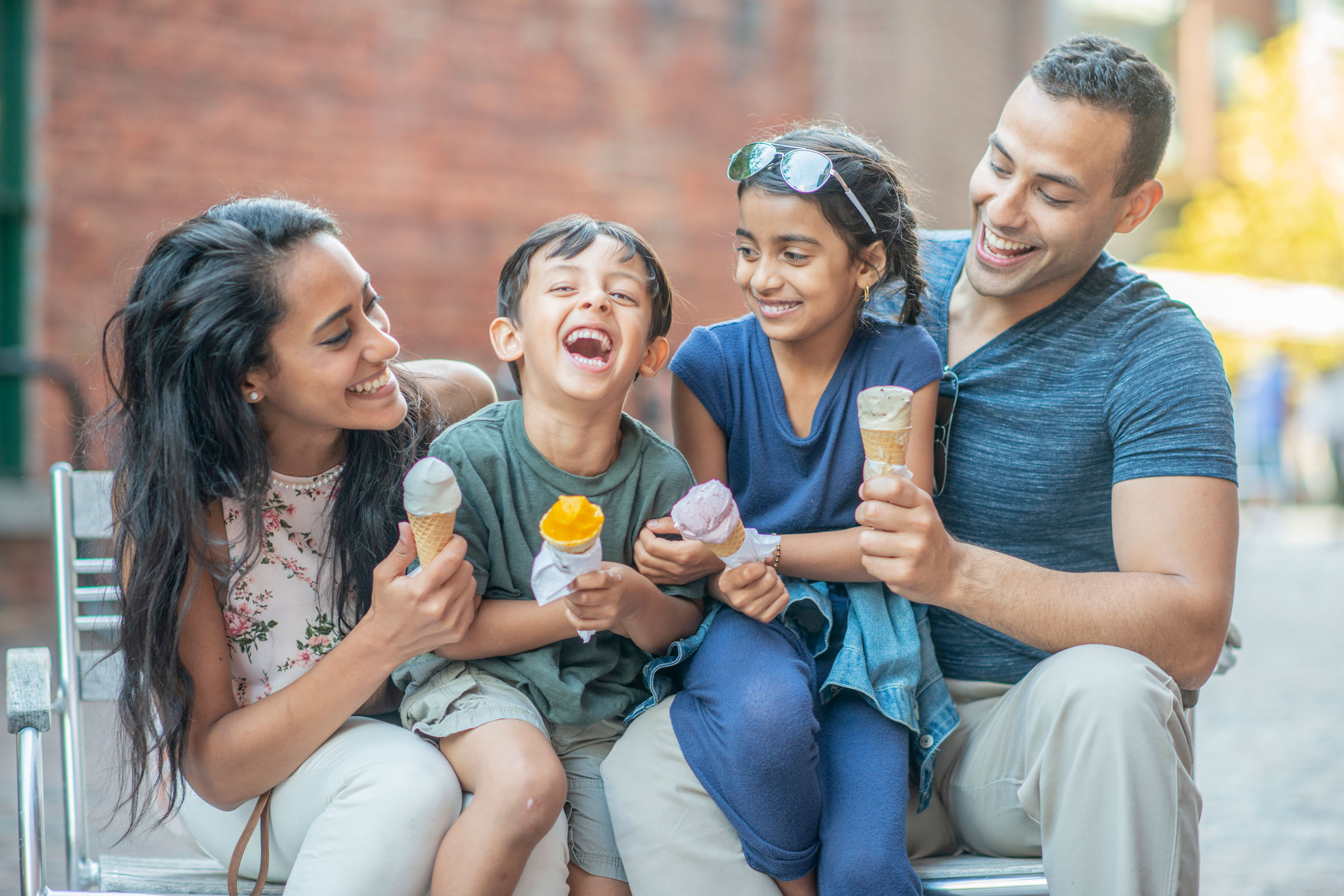 Young family eating ice cream on a bench