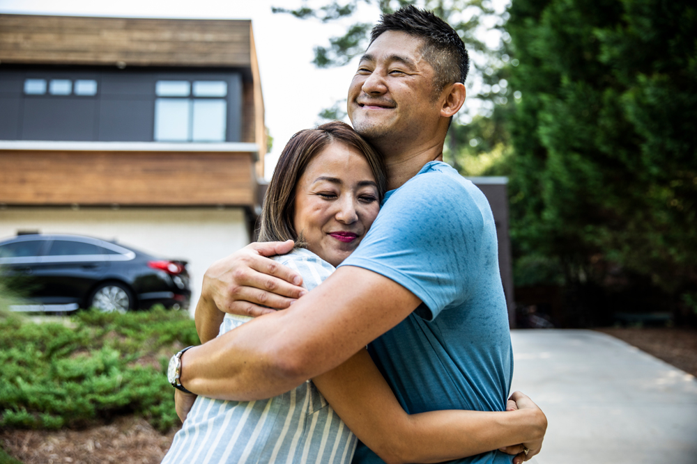 Couple embracing outside of their home