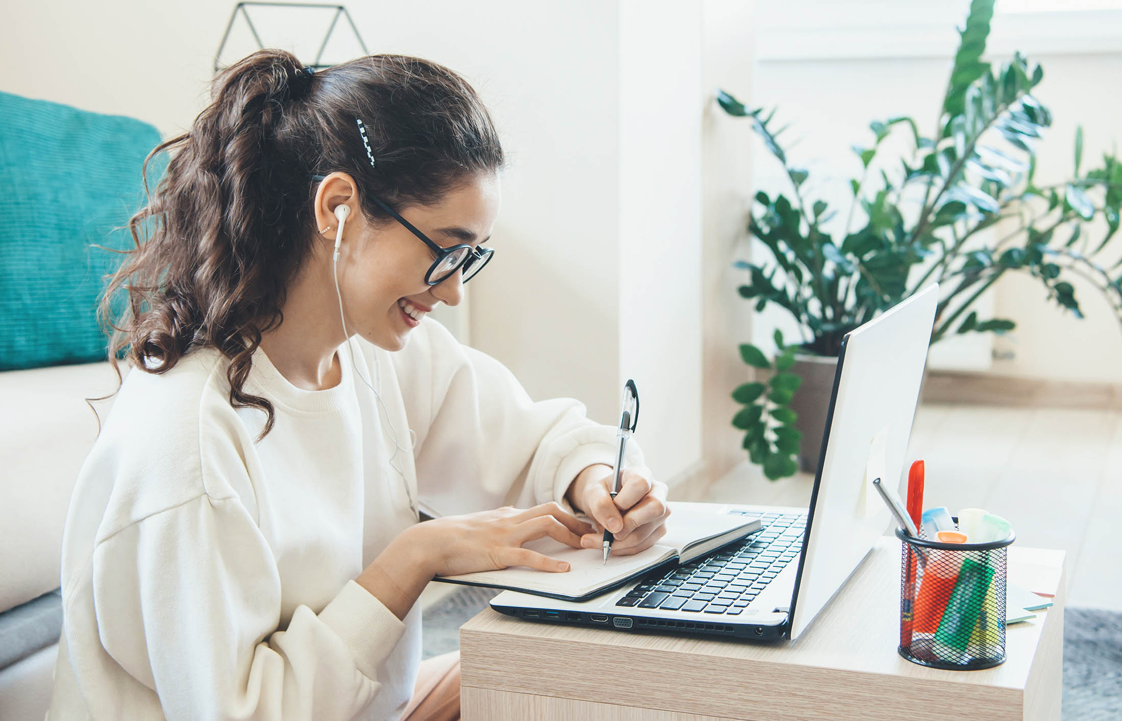 young women on computer writing in a notepad