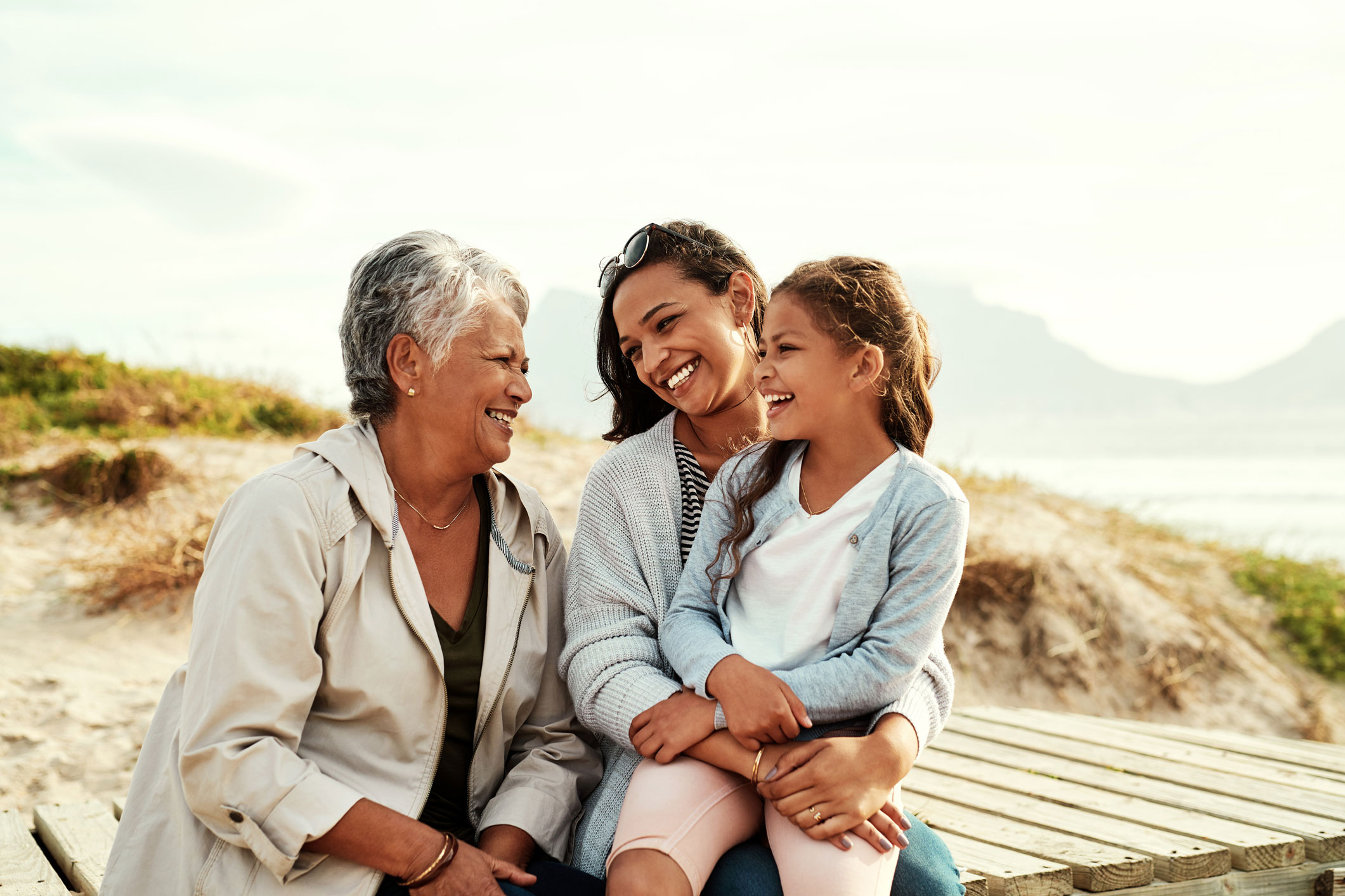 Multi-generational family sitting on picnic table and smiling
