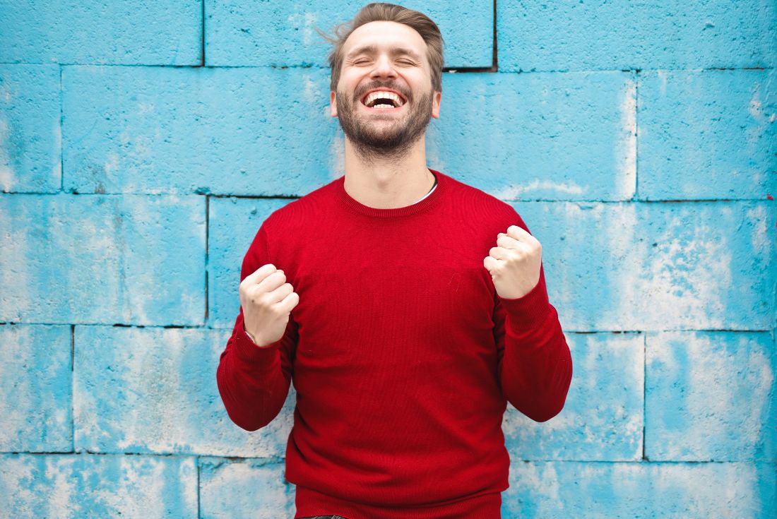 Man smiling against a blue wall