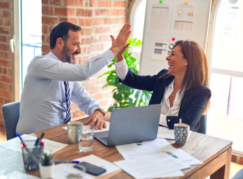 Two professionals high-fiving each other over a desk