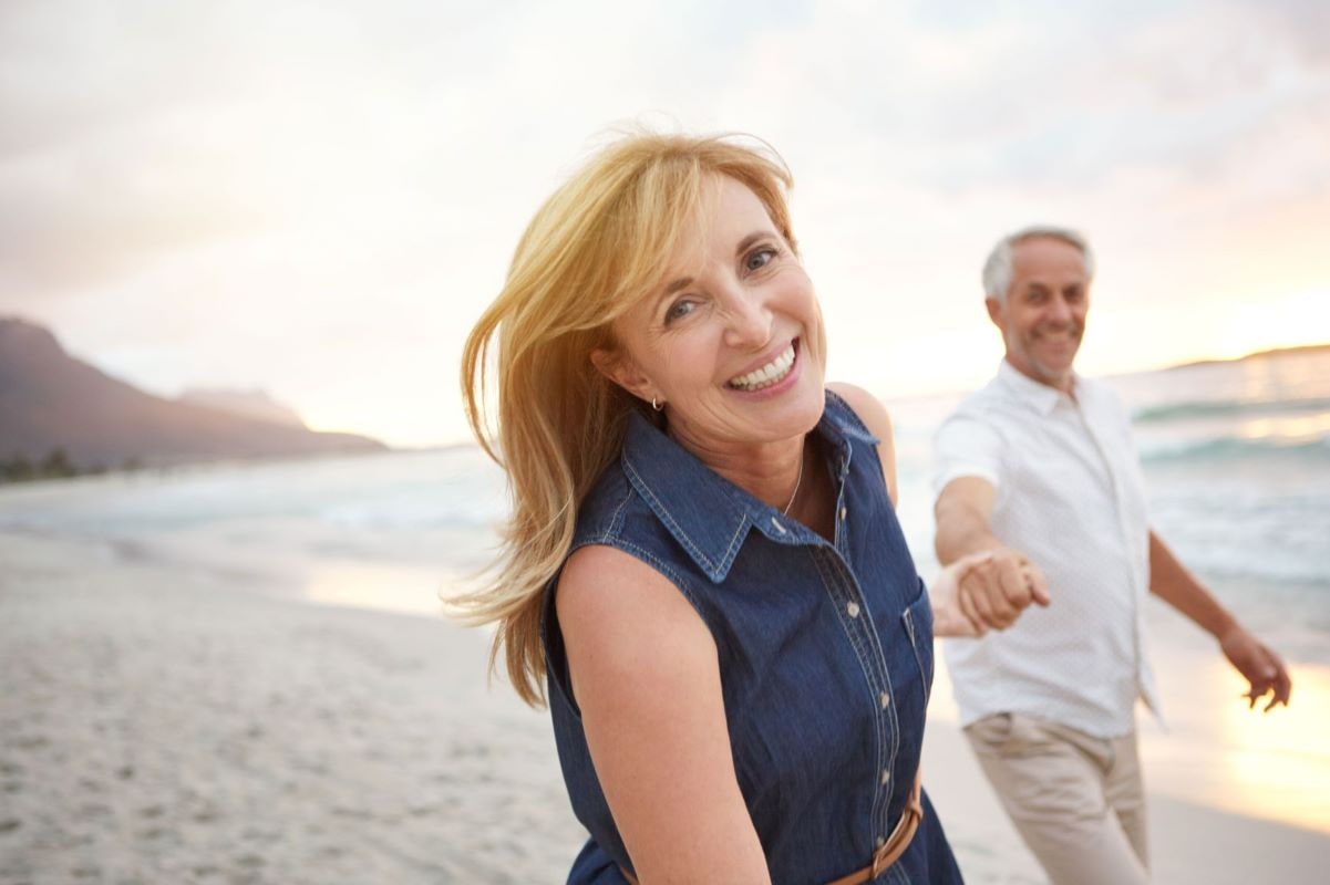 A couple on a beach holding hands smiling