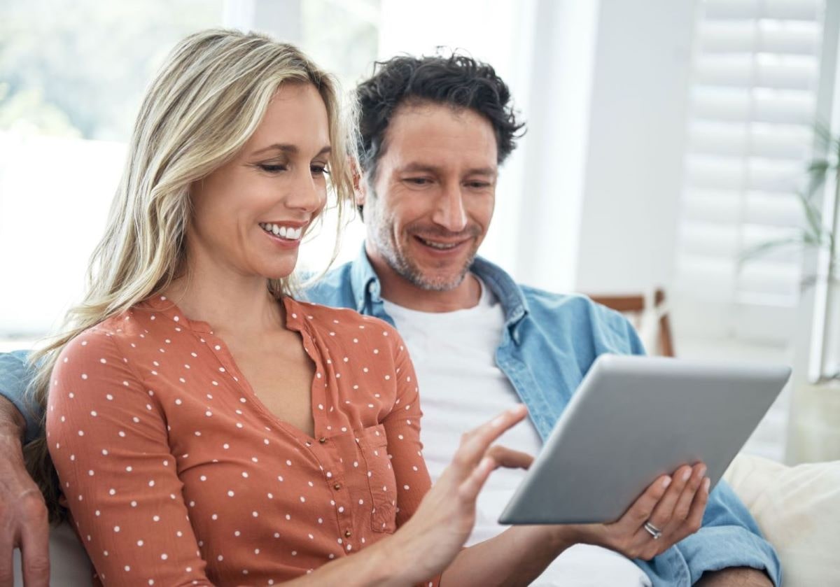 couple smiling and looking at tablet