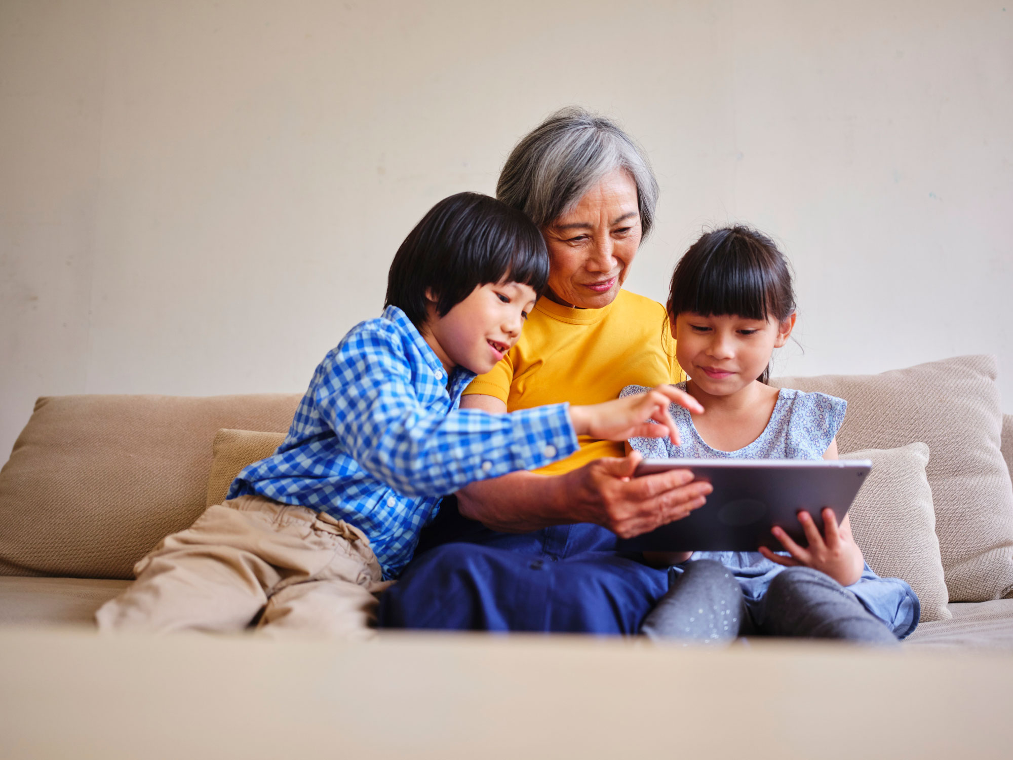 Grandmother viewing tablet with grandchildren