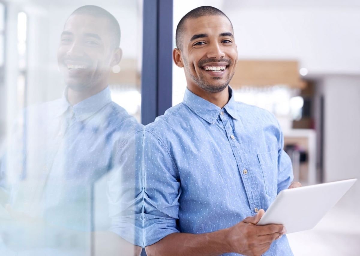 A man at the office smiling holding a tablet