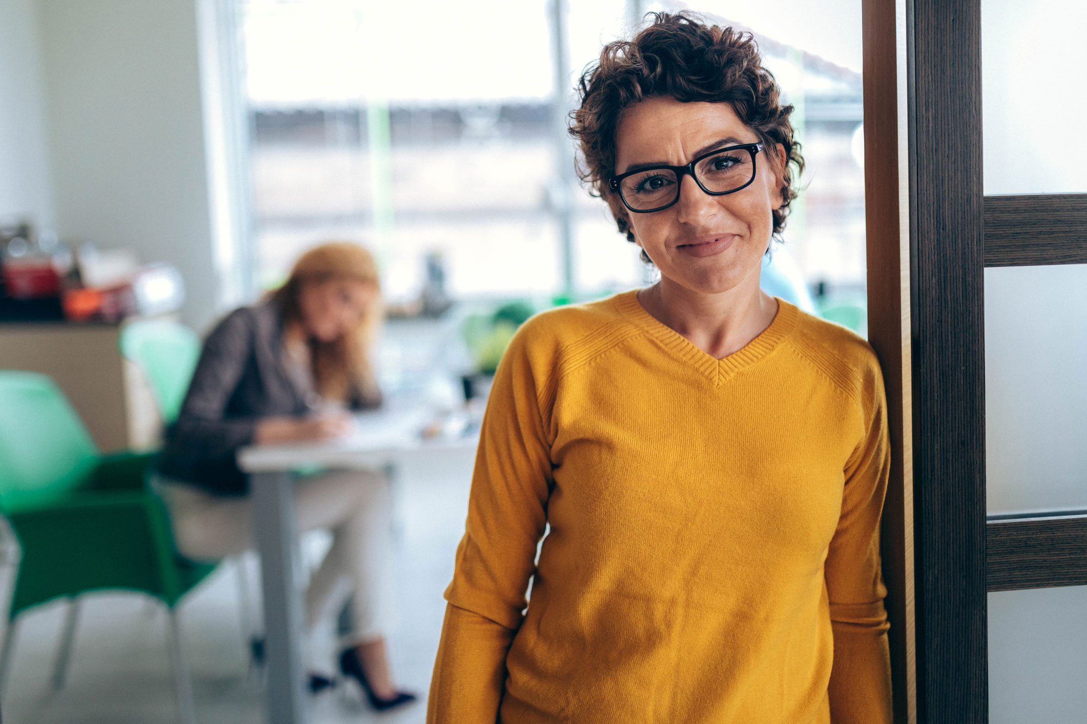 Femme à lunettes au bureau et souriante