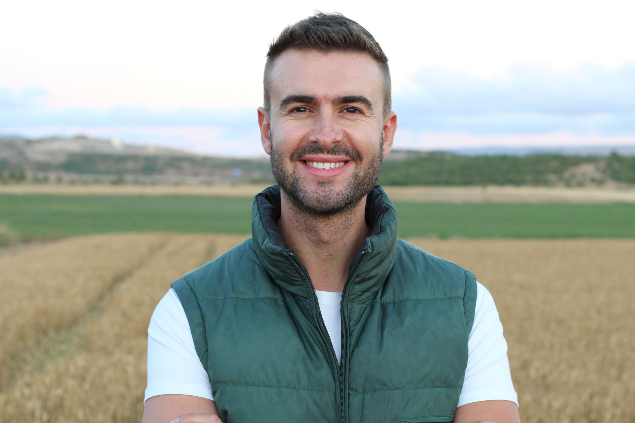 Man smiling standing in front of field