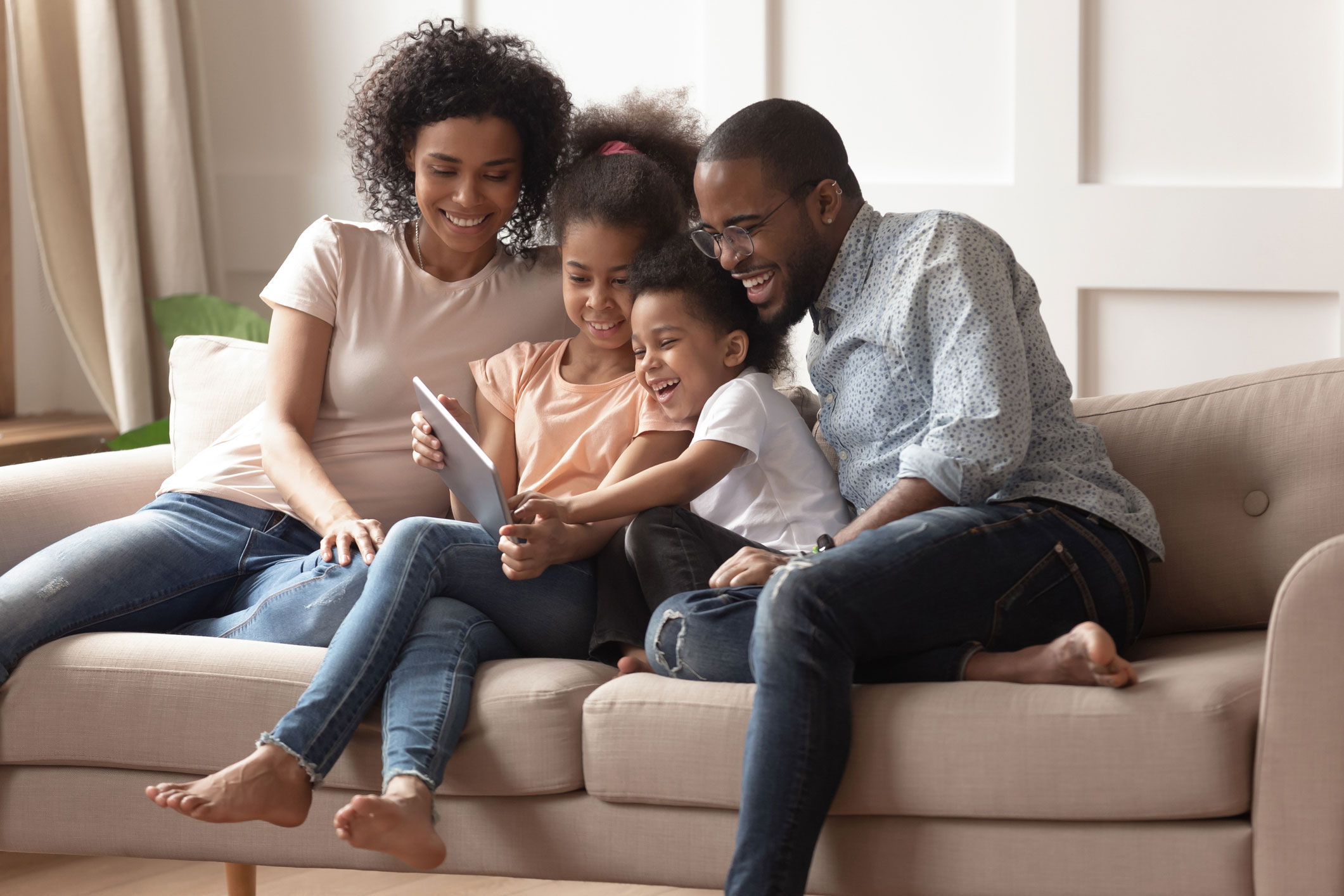 Young family viewing tablet on couch.