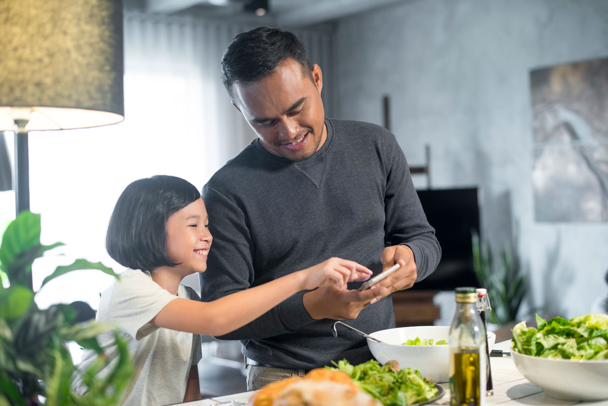 Young father viewing phone with daughter.