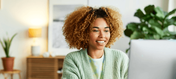 A smiling woman works at her computer.