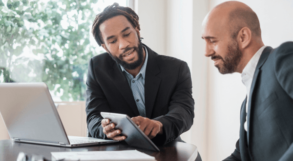 A businessman shows a colleague some details on his tablet.