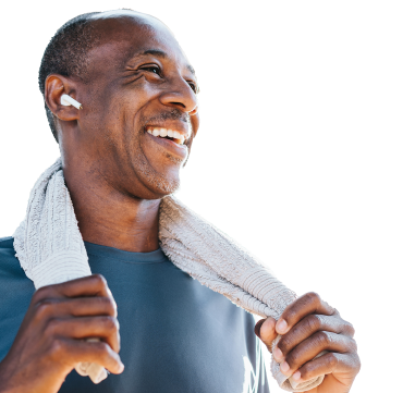 Smiling, athletic man with a shaved head wearing an earbud wraps a towel around his neck.