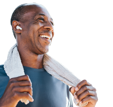 Smiling, athletic man with a shaved head wearing an earbud wraps a towel around his neck.