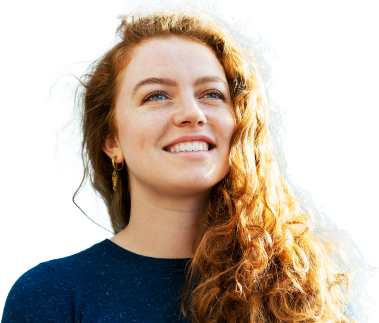 Young woman with long wavy hair looks into the distance with an optimistic smile.
