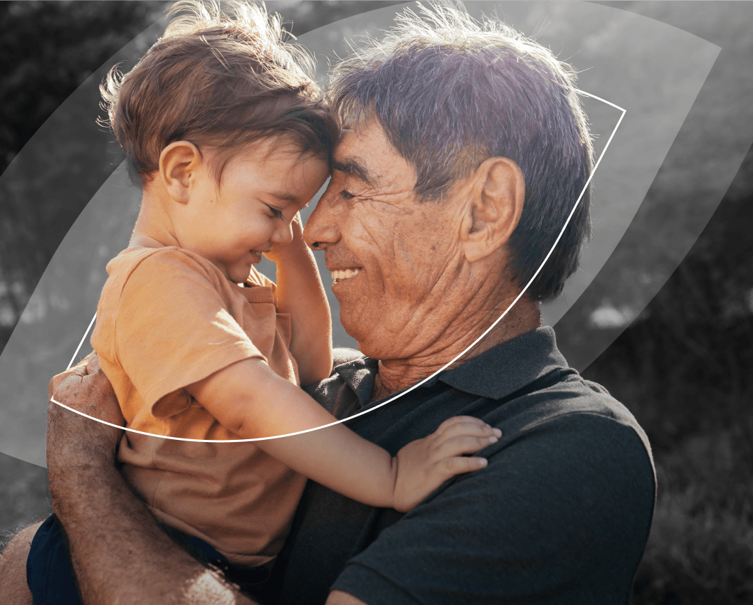 Grand-père tenant son petit-enfant et se souriant.